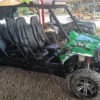 A green four-seat buggy parked on gravel with more vehicles lined up behind