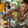 cacao-recrop A guest turning a hand-cranked mill to grind roasted cacao at a Dominican countryside home, with ground cacao on a plate beside her