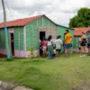 Visiting a countryside home Guests gathered at the door of a green and pink timber house in the countryside