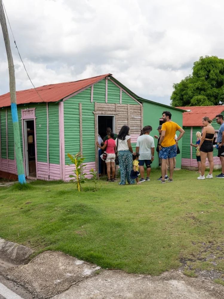 Guests gathered at the door of a green and pink timber house in the countryside