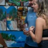 Local craft and painting shop Two guests laughing with a Dominican painter among his canvases at a roadside craft shop