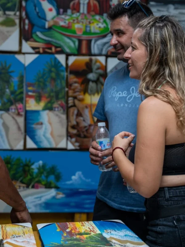 Local craft and painting shop Two guests laughing with a Dominican painter among his canvases at a roadside craft shop