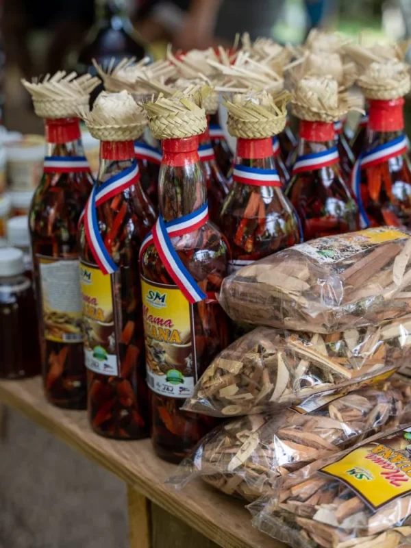 Mama Juana and local products Bottles of Mama Juana with woven straw caps beside bagged bark and root mixes for sale