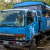 Open safari truck on the countryside route An open safari truck carrying guests along a dirt road through dense green countryside
