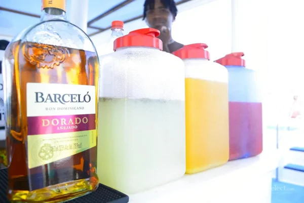 A bottle of Barcelo rum stands beside jugs of juice mixers at the boat drinks station