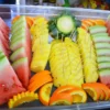 A tray of sliced watermelon, carved pineapple and orange laid out on board