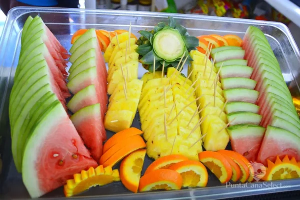 A tray of sliced watermelon, carved pineapple and orange laid out on board