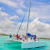 Guests gather on the bow of the catamaran Esmeralda under sail on turquoise water