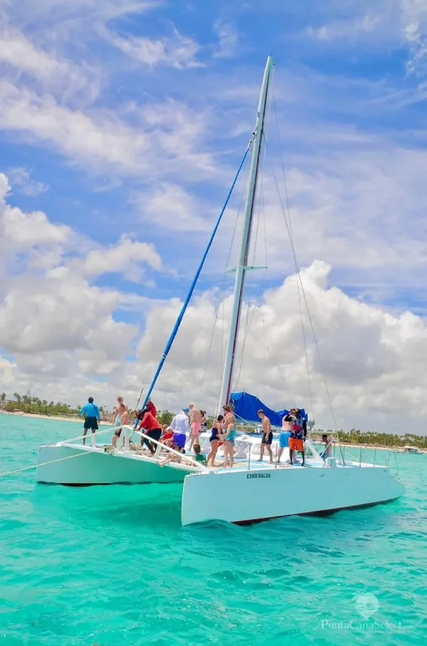 Guests gather on the bow of the catamaran Esmeralda under sail on turquoise water