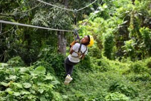A young rider in a yellow helmet looks up at the cable while crossing the zipline