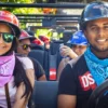 A couple in helmets and bandanas smile from the front seats of a buggy