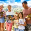 A family of five stands at a viewpoint rail with squirrel monkeys perched on their arms