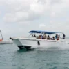 La Cherna speedboat under way off Saona Island Guests wave from the deck of the La Cherna speedboat as it powers across open water off Saona Island, with a catamaran anchored behind