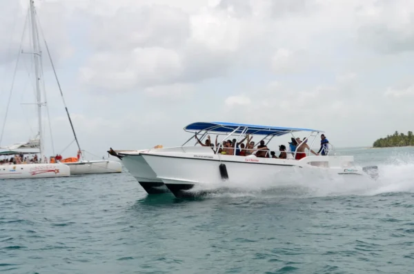 La Cherna speedboat under way off Saona Island Guests wave from the deck of the La Cherna speedboat as it powers across open water off Saona Island, with a catamaran anchored behind