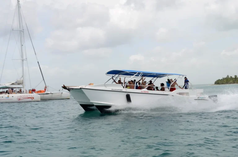Guests wave from the deck of the La Cherna speedboat as it powers across open water off Saona Island, with a catamaran anchored behind