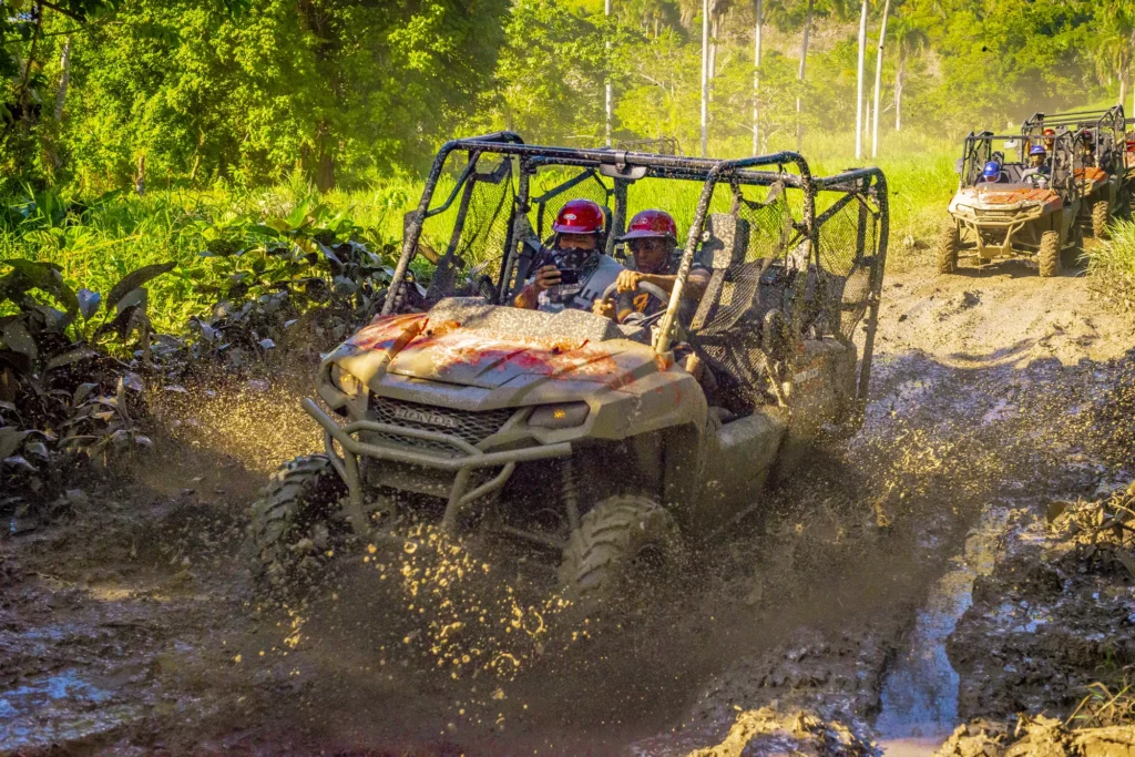 A mud-covered buggy drives through a deep rutted puddle in open country