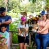 A family stands at a wooden rail with squirrel monkeys perched on their shoulders and arms, bright croton leaves behind