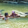 Three guests stand chest-deep in the Anamuya River laughing together