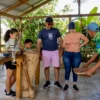 Guests take turns grinding cacao with a wooden pestle while a local guide demonstrates at the Coconut House