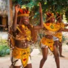 Dancers in feathered headdresses and painted body art perform an ancestral dance in the Taíno village clearing