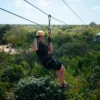 A guest glides along a zipline high above the jungle canopy with the treetops stretching to the horizon