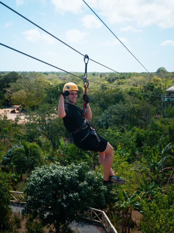 A guest glides along a zipline high above the jungle canopy with the treetops stretching to the horizon
