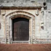 A carved stone rope moulding framing the arched wooden doorway of a sixteenth-century colonial house