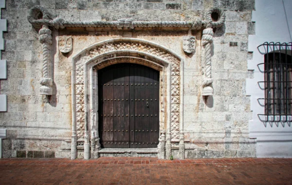 A carved stone rope moulding framing the arched wooden doorway of a sixteenth-century colonial house