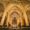 The vaulted stone nave of the first cathedral of the Americas lit warmly above its golden high altar