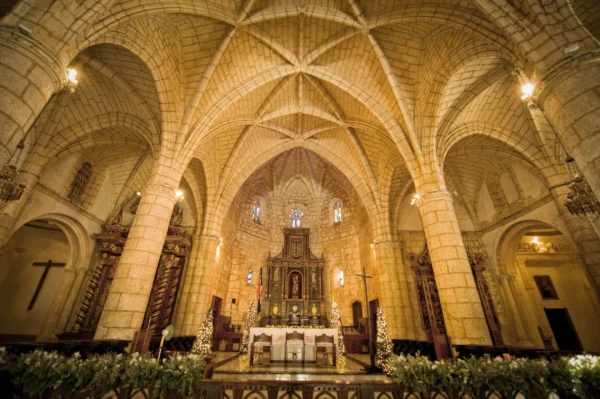 The vaulted stone nave of the first cathedral of the Americas lit warmly above its golden high altar