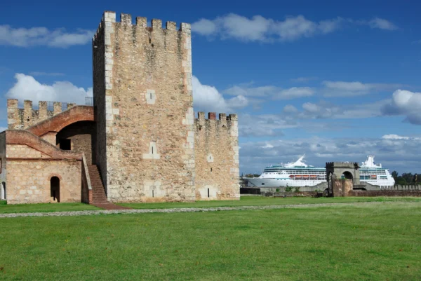 The crenellated Tower of Homage at the Fortaleza Ozama seen across a wide green lawn