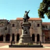 The Christopher Columbus monument standing in Parque Colon with the walls of the first cathedral behind it