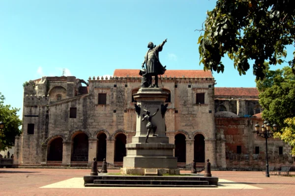 The Christopher Columbus monument standing in Parque Colon with the walls of the first cathedral behind it