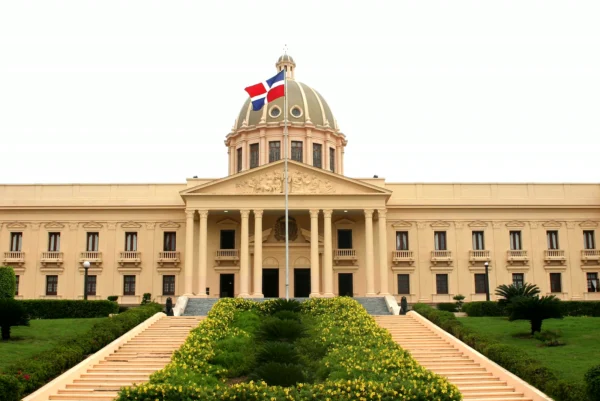 The domed National Palace behind terraced steps and flowering gardens with the Dominican flag flying